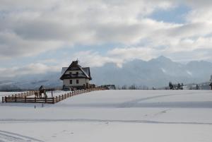 une maison sur une colline enneigée avec une clôture dans l'établissement Willa Misiowa Chata, à Czarna Góra