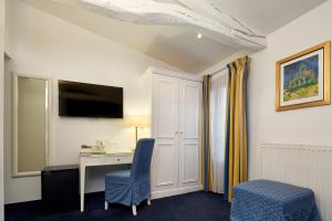 a room with a desk and a chair and a tv at Austin's Arts Et Metiers Hotel in Paris