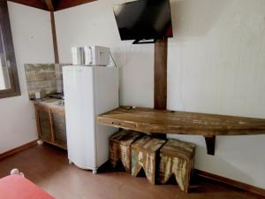 cocina con nevera blanca y mesa de madera en Pousada Águas de Ibiraquera Suíte Luz en Imbituba