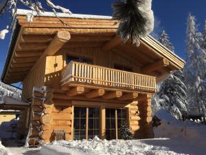 Cette cabane en rondins dispose d'un balcon dans la neige. dans l'établissement Chalet Karin, à Hochfilzen