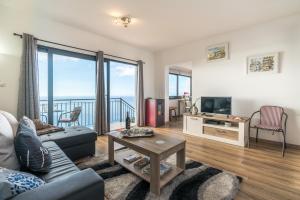 a living room with a couch and a tv at Casa da Tenda in Arco da Calheta