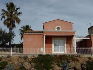 een roze huis met een palmboom op de achtergrond bij Villa avec piscine in Cap d'Agde