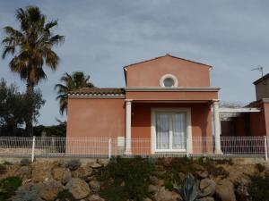 a pink house with a palm tree in the background at Villa avec piscine in Cap d'Agde