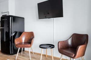 twee stoelen en een tafel met een tv aan de muur bij Apartment Station in Oulu