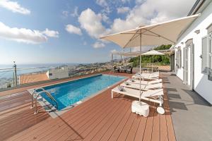 a deck with a pool and chairs and an umbrella at OurMadeira - Vila da Portada, character in Funchal