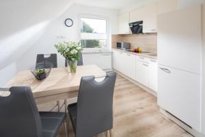 una cocina con armarios blancos y una mesa de madera con sillas. en Deniz - Blick, en Norderney
