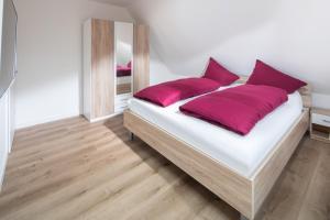 un grande letto con cuscini rossi in una stanza di Deniz - Blick a Norderney