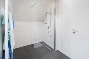ein Bad mit einer Dusche und weißen Fliesen in der Unterkunft Deniz - Blick in Norderney