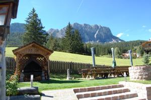 a picnic table and benches in a field with mountains at Chalet alla Cascata in Badia