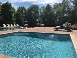 a couple sitting in a chair next to a swimming pool at Hotel Casa Real - Viña Santa Rita in Santiago