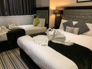 two beds in a hotel room with swans on them at The W14 Kensington in London
