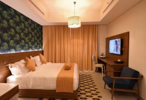 een slaapkamer met een bed, een bureau en een televisie bij Flamingo Hotel in Jeddah