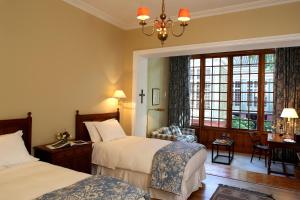a hotel room with two beds and a chair at Hotel Casa Real - Viña Santa Rita in Santiago