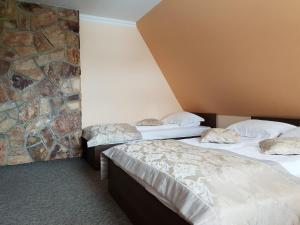 two beds in a room with a stone wall at Ostrysz in Dzianisz