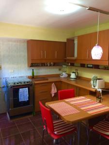 a kitchen with wooden cabinets and a table with red chairs at Casa confortable, campo y playa in Buchupureo