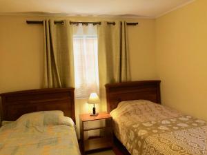 two beds in a small bedroom with a window at Casa confortable, campo y playa in Buchupureo