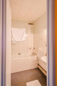a white bathroom with a tub and a sink at Le Commerce in Dompaire