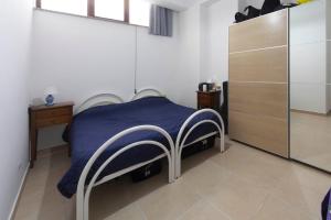 a bedroom with a bed with a blue blanket and a cabinet at Apartments d'Orlando - 2 bedrooms apartment with garden in Capo dʼOrlando