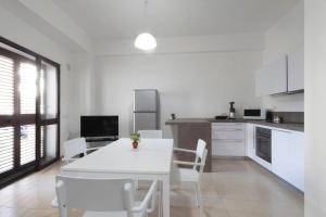 a white kitchen with a white table and chairs at Apartments d'Orlando - 2 bedrooms apartment with garden in Capo dʼOrlando