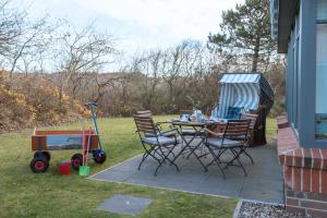 eine Terrasse mit einem Tisch, Stühlen und einem Wagen in der Unterkunft Dünenstern in Wangerooge