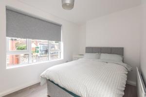 a white bedroom with a bed and two windows at The Gem in Armagh