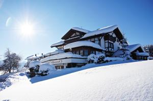 una casa cubierta de nieve en la cima de una colina cubierta de nieve en Gästehaus Alpenruh, en Fischen