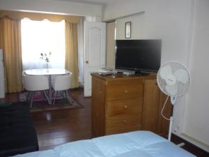 1 dormitorio con 1 cama, TV y mesa en Rodeo Departamentos Amoblados, en Rancagua
