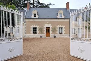 una casa vieja con una puerta blanca delante de ella en Chambres et tables d'hôtes Le Voriou, en Couddes