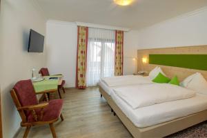 um quarto de hotel com uma cama grande e uma mesa em Hotel Wechselberger em Saalbach-Hinterglemm
