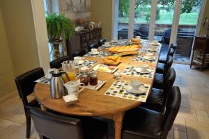 a long wooden table with black chairs around it at Chambres et tables d'hôtes Le Voriou in Couddes