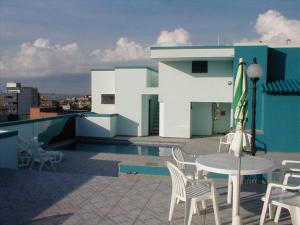 a patio with a table and chairs and an umbrella at Crystal Apart Hotel in Macaé