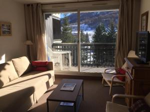 ein Wohnzimmer mit Couch und großem Fenster in der Unterkunft Appartement Pied de pistes et Coeur de station in La Salle Les Alpes
