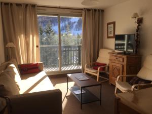 ein Wohnzimmer mit einem Sofa, einem TV und einem Fenster in der Unterkunft Appartement Pied de pistes et Coeur de station in La Salle Les Alpes
