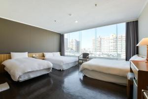 Una habitación de hotel con dos camas y una gran ventana. en Back Home Hotel, en Chiayi