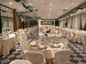 um grande salão de banquetes com mesas e cadeiras brancas em Platani Hotel em Bolsena mais 37 fotografias