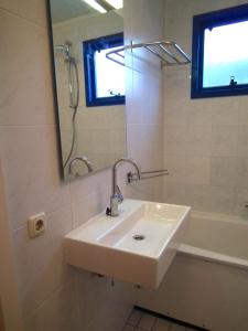 un bagno con un lavandino, uno specchio e una vasca di Hollumerstrand a Hollum