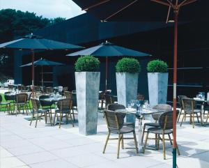 an outdoor patio with tables and chairs and umbrellas at mour hotel in Mansfield