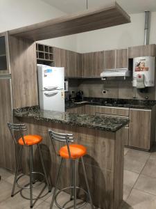 een keuken met 2 barkrukken en een koelkast bij Los Talas in Villa Carlos Paz