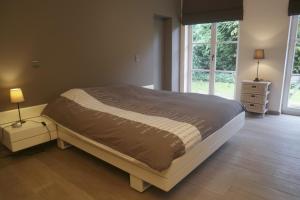 a bedroom with a large bed with two night stands and a window at Villa Kokeliko in Kuurne