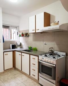 a kitchen with white cabinets and a stove top oven at Alojamiento Monte Hermoso in Monte Hermoso