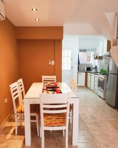 a white dining room table with chairs and a kitchen at Alojamiento Monte Hermoso in Monte Hermoso