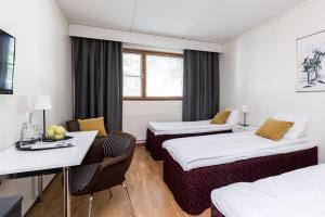 タンペレにあるHotel Hermicaのベッド2台、テーブルと椅子が備わるホテルルームです。