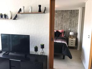 a living room with a television and a bed at Espectacular departamento frente al casino!! in Viña del Mar