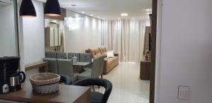 uma sala de estar com uma mesa e um sofá em Excelente Apto Terraço Verde C/Vista Mar Piscina 3 D em Capão da Canoa mais 33 fotografias