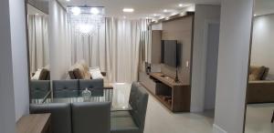 uma sala de estar com uma mesa de vidro e uma televisão em Excelente Apto Terraço Verde C/Vista Mar Piscina 3 D em Capão da Canoa