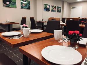 a dining room with wooden tables with white plates on them at Hotel Mirabell in Erlangen