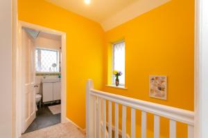 a yellow room with a crib and a window at Astley in Leicester