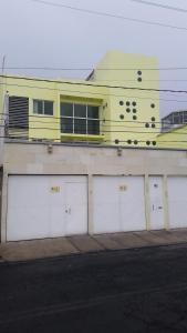 a yellow building with four garage doors and a building at Departamento cómodo y completo en Toluca in Toluca