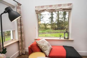 a living room with a red couch and a window at The Wild Farm Cottage in Mullingar