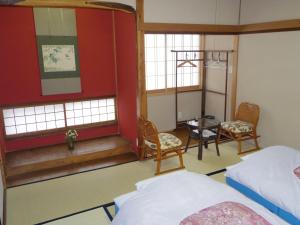 um quarto com uma cama, uma mesa e cadeiras em Guest House Motomiya em Nakatsugawa